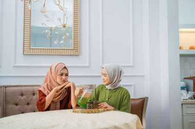 Asian woman in hijab serves drinks when her friend is sad at home