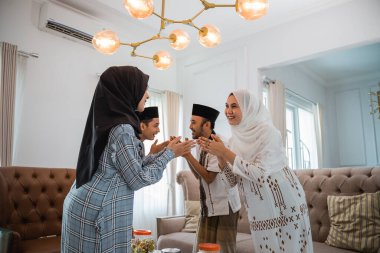 two Muslim couples visit with a hand gesture to forgive each other when they meet at home during Eid celebration