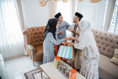 Two Muslim couples meet to celebrate Eid day at home in the living room