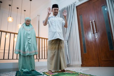 Asian man becomes prayer leader with woman behind him during home prayers