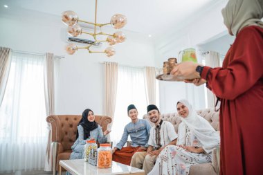 Veiled women carry trays of drinks to serve to friends during Eid celebrations together at home