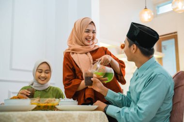 wife serves drink to husband while breaking fast at the dining table