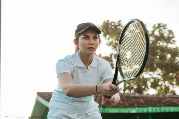 Female tennis athlete concentrating while holding a racket on the court