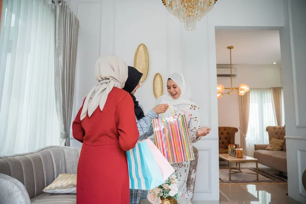 two women in veil come carrying paper bag gifts for a friend during a visit home to celebrate Eid