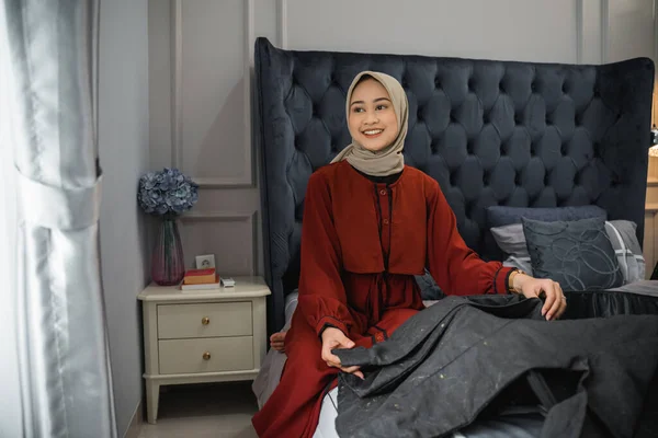 Beautiful Woman Hijab Smiles Looking Window While Folding Clothes Sitting — Stock fotografie