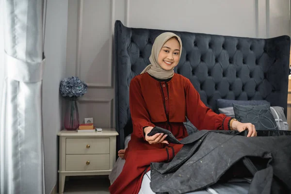 Žena Hidžábu Usmívá Při Skládání Oblečení Sedí Posteli — Stock fotografie