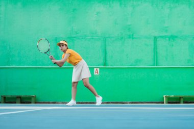 female tennis player ready to receive ball while holding racket on tennis court