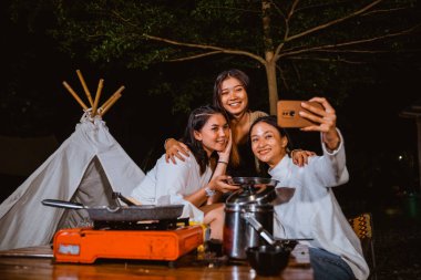 a group of women taking groufie photo while camping together at the camp site