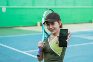 blank phone screen shown by female tennis player on tennis court