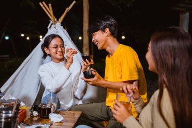 woman in white knit sweater feeding the guy in yellow t shirt that sitting next to her
