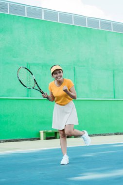 female excited tennis player after hitting the ball to score with racket on tennis court