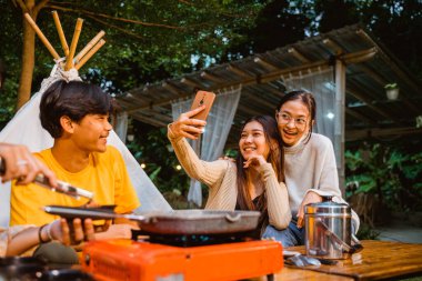 two beautiful women taking a groufie photo and smiling while hangout together at the camp site