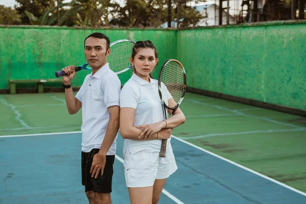 Asian tennis athletes standing back to back on the tennis court