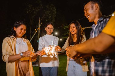 a group of people standing in circle and put their fireworks together while camping at the camp site