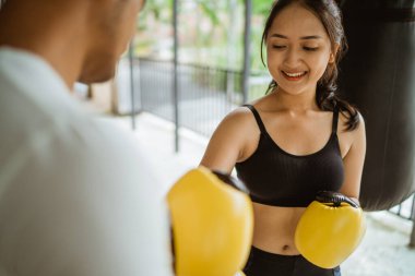 Erkek boks koçunun yardımıyla boks eldivenlerini giyerek boks yapan bir bayan boksör.