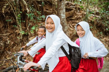 Üç ilkokul öğrencisi sabahları okula bisikletle gidiyor.