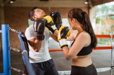 Bir kadın boksör, boksör erkeğin çenesini yumrukluyor.