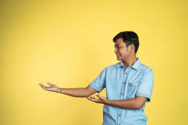 Asyalı bir adamın portresi. Elleri yanlamasına, izole edilmiş arka planda bir şey gösteriyor.