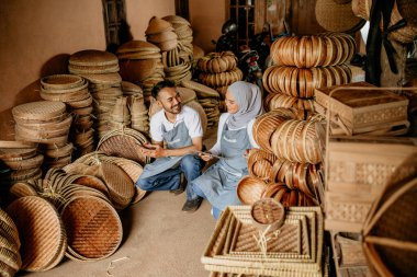 Mutlu Asyalı el sanatları ustası dükkânda dokuma bambu ürünleri üzerinde çalışıyor.