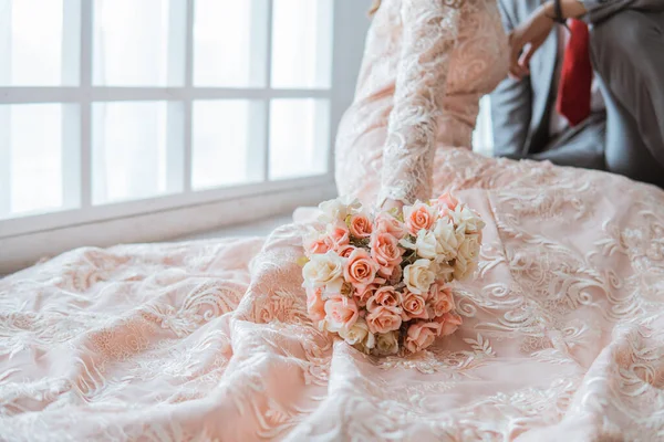 花束を持ったアジア系の花嫁が新郎の横の床に座り — ストック写真