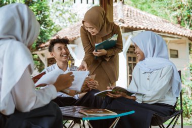 Bayan öğretmen dışarıda çalışırken öğrencilere tavsiye veriyor.