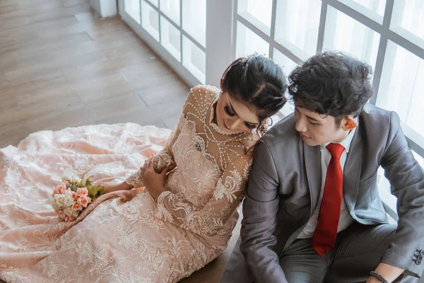 Asijské Nevěsta Opírající Ženicha Zatímco Sedí Společně Podlaze Vedle Okna — Stock fotografie