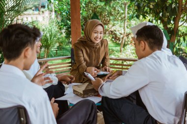 Veil 'deki öğretmen öğrencilere açık hava dersi sırasında çardaktaki soruları sormaları için rehberlik ediyor.