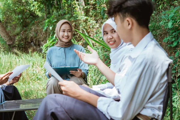 stock image the teacher watches as one of the students is presenting during an outdoor class