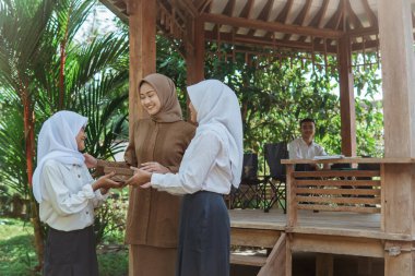 Öğretmen odanın dışında iki kız öğrenciye rehberlik ederken sohbet ediyor.
