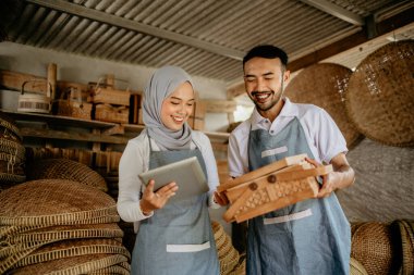 Erkekler ve kadınlar geleneksel ürün dükkanlarında çalışırken tablet bilgisayar kullanıyorlar.