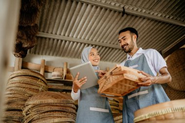 Erkekler ve kadınlar geleneksel ürün dükkanlarında çalışırken tablet bilgisayar kullanıyorlar.
