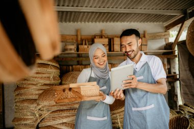 Erkekler ve kadınlar geleneksel ürün dükkanlarında çalışırken tablet bilgisayar kullanıyorlar.