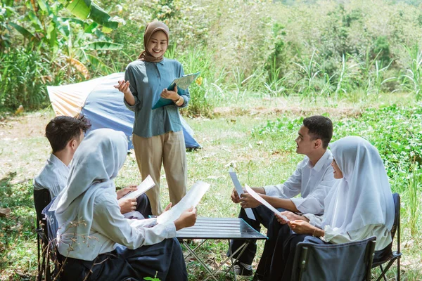 アジア系イスラム教徒の教師が野外授業で中学生に教える — ストック写真