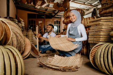 Mutlu Asyalı el sanatları ustası dükkânda dokuma bambu ürünleri üzerinde çalışıyor.