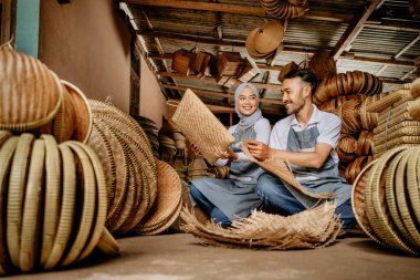 Mutlu Asyalı el sanatları ustası dükkânda dokuma bambu ürünleri üzerinde çalışıyor.
