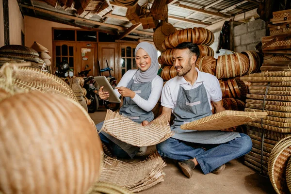 アジア系イスラム教徒の女性とそのパートナーは竹製品を伝統的な倉庫で確認し — ストック写真
