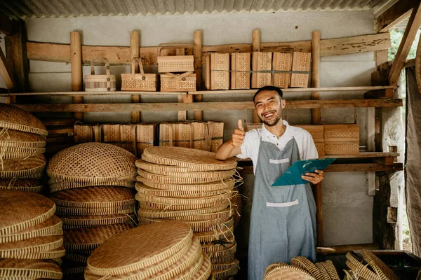 Geleneksel bambu satıcısı kameraya gülümsüyor ve parmağını kaldırıyor.
