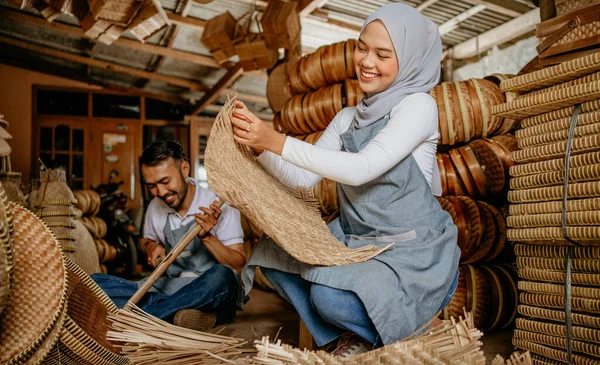 İki işçinin portresi atölyesinde geleneksel bambu ürünleri dokuyor.