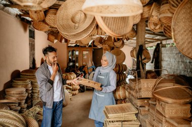 Örgü bambu satıcısı ürünlerini dükkânda müşteriye sunuyor.