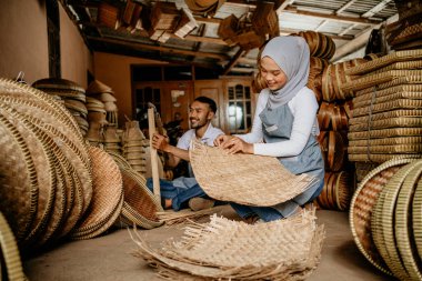 İki işçinin portresi atölyesinde geleneksel bambu ürünleri dokuyor.