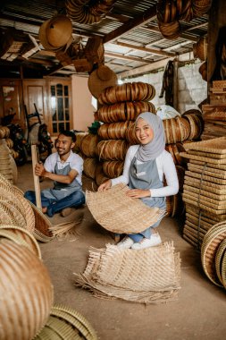 Mutlu Asyalı el sanatları ustası dükkânda dokuma bambu ürünleri üzerinde çalışıyor.