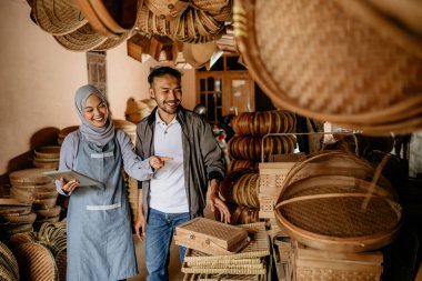 Geleneksel bambu ürünleri atölyesinde müşterisi olan çekici Müslüman kadın satıcı.