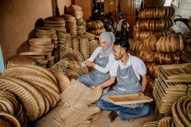 İki işçinin portresi atölyesinde geleneksel bambu ürünleri dokuyor.