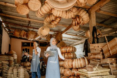Erkekler ve kadınlar geleneksel ürün dükkanlarında çalışırken tablet bilgisayar kullanıyorlar.