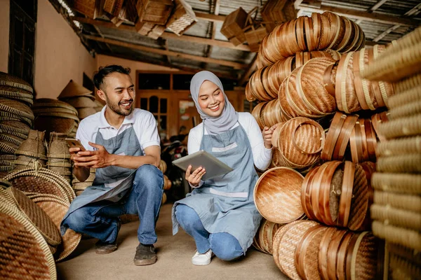 アジア系イスラム教徒の女性とそのパートナーが竹製品をチェックしています — ストック写真