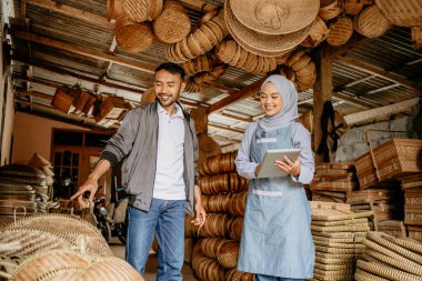 Geleneksel bambu ürünleri atölyesinde müşterisi olan çekici Müslüman kadın satıcı.