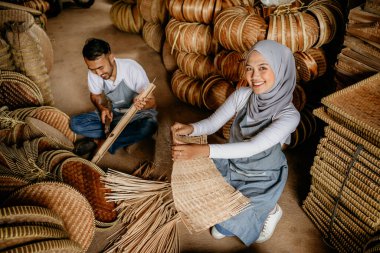İki işçinin portresi atölyesinde geleneksel bambu ürünleri dokuyor.