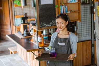 Önlüklü bayan barista tepsiyi getir.