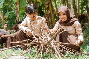 Kız izciler ve erkek izciler doğada kamp yaparken kuru dallar düzenlerler.