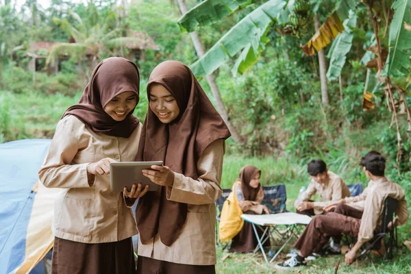 Dua Gadis Pramuka Memakai Tabir Menggunakan Tablet Digital Terhadap Latar — Stok Foto